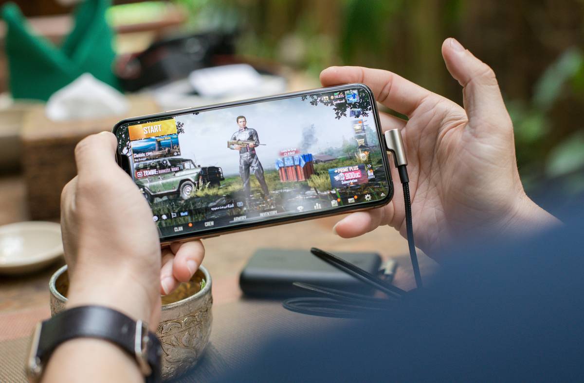 Player holding smartphone with overlay showing stats, labeled home of competitive gaming